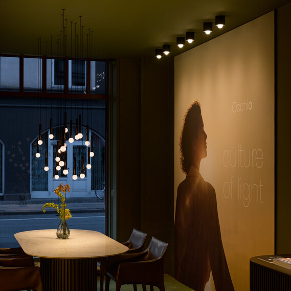 Occhio coro moon wave led pendant in showroom copenhagen over dining table green velvet surrounding