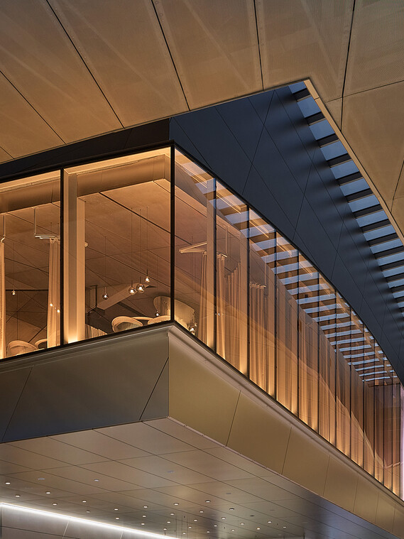Außenansicht von The Cloud by Käfer – die schwebende Struktur in der BMW Welt München bei Abendlicht, mit Blick auf die verglaste Architektur und das darüber liegende Restaurant.