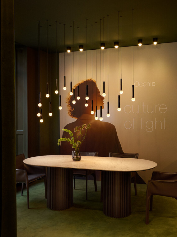 Occhio coro moon wave led pendant in showroom copenhagen over dining table green velvet surrounding