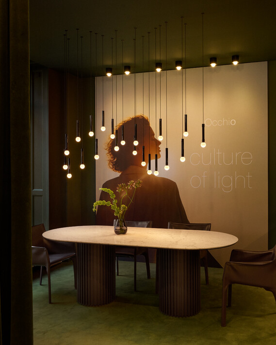 Occhio coro moon wave led pendant in showroom copenhagen over dining table green velvet surrounding