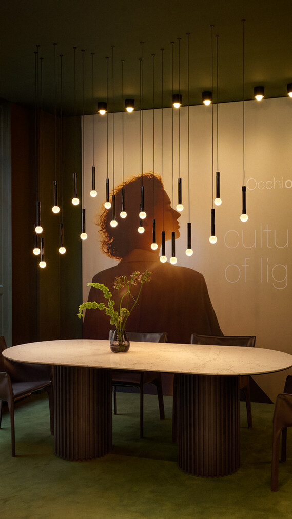 Occhio coro moon wave led pendant in showroom copenhagen over dining table green velvet surrounding